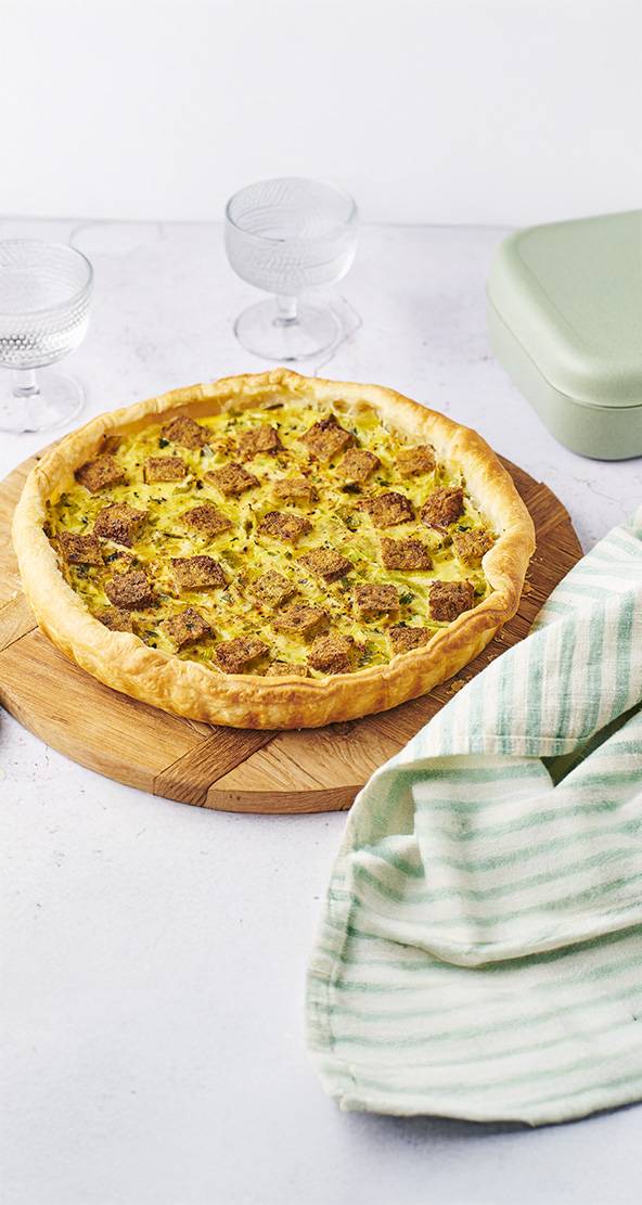 Une tarte savoureuse garnie de croutons dorés, servie sur une planche en bois.