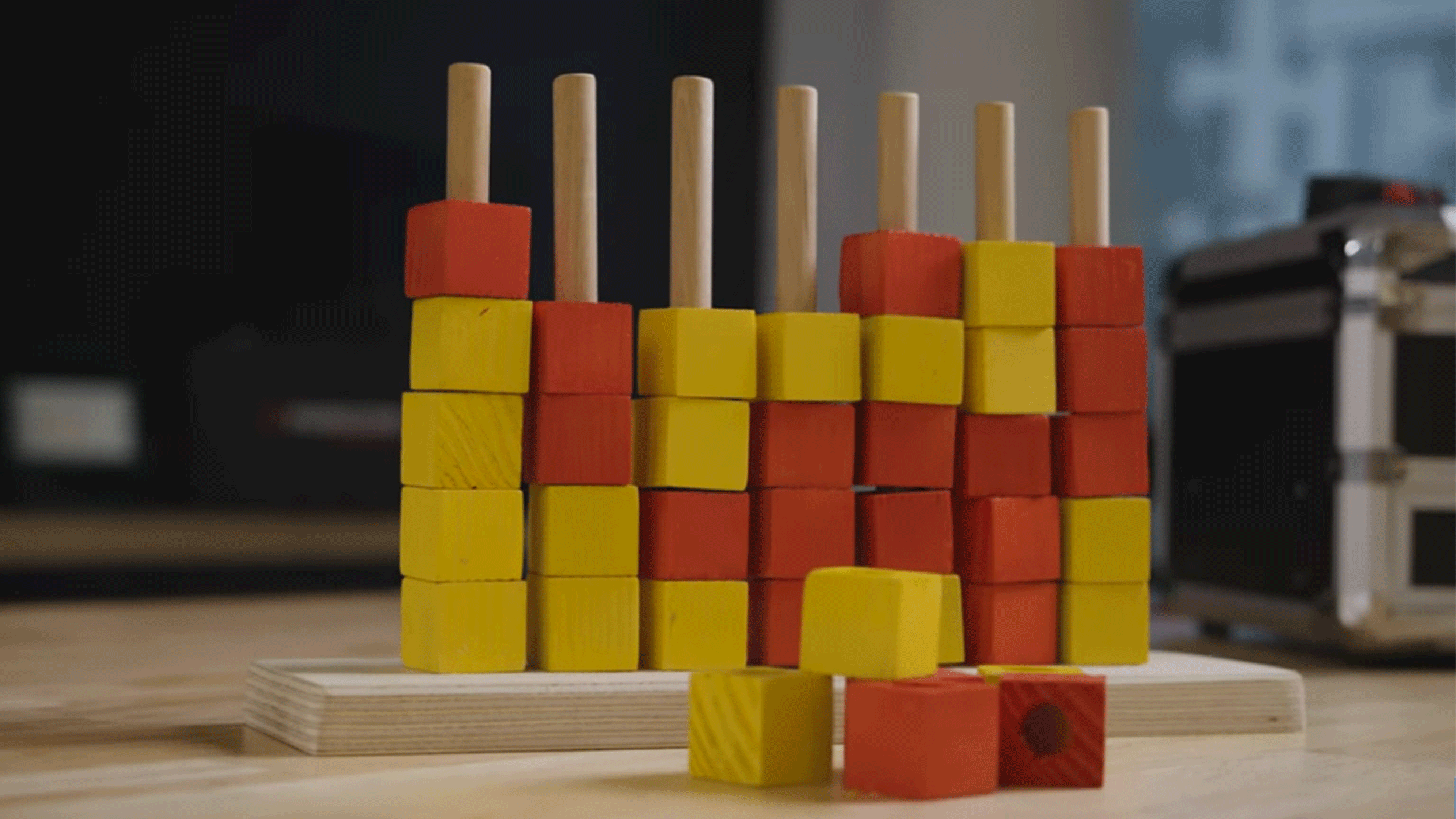 Jeu d'empilage en bois rouge et jaune avec des piquets sur une base en bois.